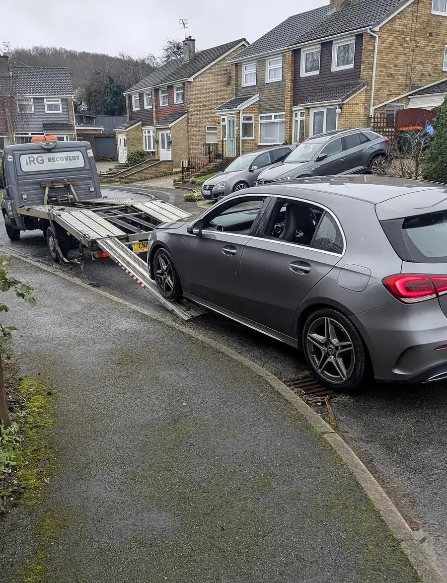 A vehicle being loaded onto a flatbed recovery truck